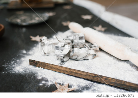 Wooden board with a pile of cookie cutters and a rolling pin on it. The scene suggests that someone is in the process of making cookies Wooden board with a pile of cookie cutters and a rolling pin on it. The scene suggests that someone is in the process of making cookies 118266675