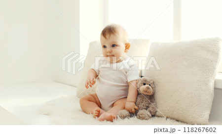 Happy cute little baby playing with teddy bear toy in white room at home Happy cute little baby playing with teddy bear toy in white room at home 118267602