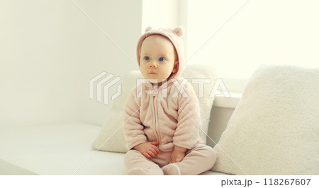 Cute little baby sitting on the floor in bathrobe in white room at home Cute little baby sitting on the floor in bathrobe in white room at home 118267607