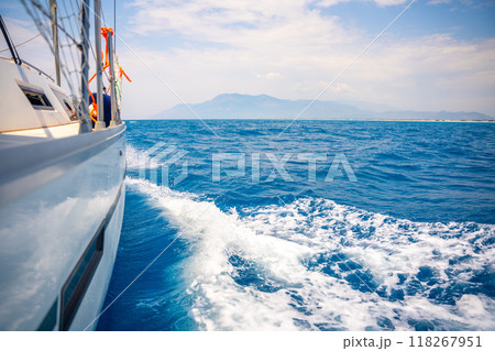 Yacht sailing in an open sea. Close-up view of side of the boat. Clear sky after the rain, waves and water splashes 118267951
