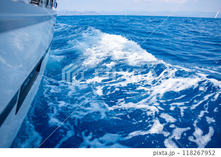 Yacht sailing in an open sea. Close-up view of side of the boat. Clear sky after the rain, waves and water splashes 118267952