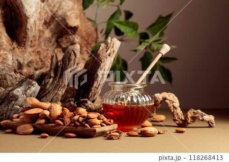 Almond nuts in a wooden dish and honey in a glass jar. Almond nuts in a wooden dish and honey in a glass jar. 118268413