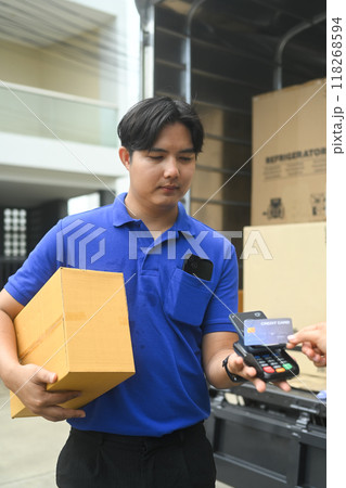 Delivery man delivering a package to a customer and receiving payment with credit card 118268594