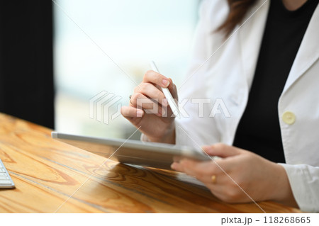 Cropped shot of businesswoman using digital tablet at wooden office desk Cropped shot of businesswoman using digital tablet at wooden office desk 118268665