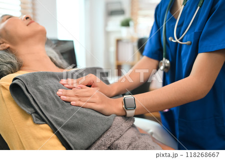 Physical therapist doing chest percussion on a senior patient to help loosen and drain secretions from her lungs 118268667
