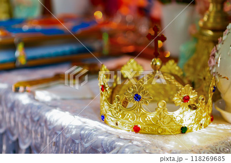 Golden Crown With Colorful Jewels Displayed on a Decorated Altar in a Serene Setting. Golden Crown With Colorful Jewels Displayed on a Decorated Altar in a Serene Setting. 118269685