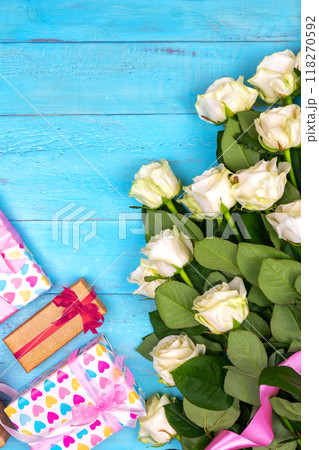 many white roses on a blue wooden background with a gift, a postcard to the day of the mother, Valentine's day or a woman's day. greeting card. place for text. top view many white roses on a blue wooden background with a gift, a postcard to the day of the mother, Valentine's day or a woman's day. greeting card. place for text. top view 118270592