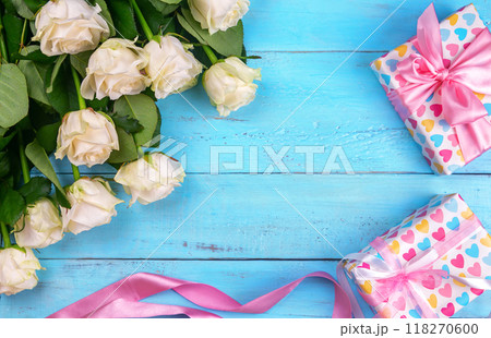 many white roses on a blue wooden background with a gift 118270600