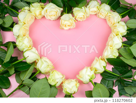 Beautiful white roses are laid out in the shape of a heart on a pink background. Beautiful white roses are laid out in the shape of a heart on a pink background. 118270602