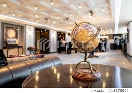 An elegant vintage classic world map model placed on a retro circle dark wood table in the hotel lobby. 118270993