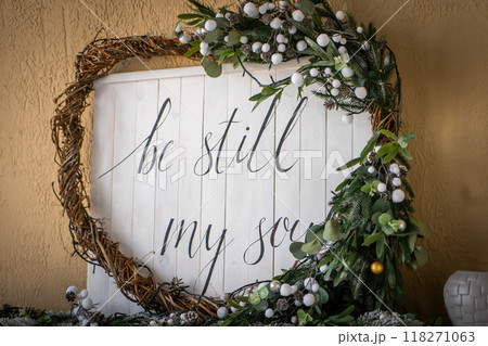 Christmas heart wreath with holly, mistletoe, ivy, pine cones and cedar leaf sprigs over white background. 118271063