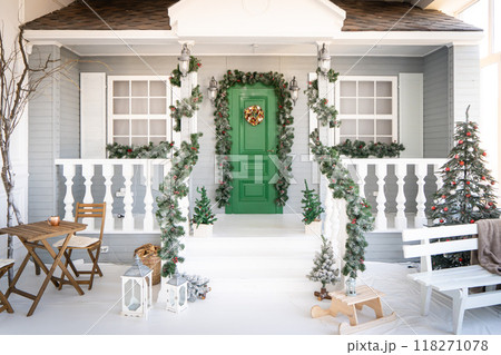 Christmas morning. porch a small house with a decorated door with a Christmas wreath. Winter fairy tale. Christmas morning. porch a small house with a decorated door with a Christmas wreath. Winter fairy tale. 118271078