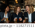 Group of women of different nationalities, dressed in business suits, sitting at bar and relaxing with beer after work 118271511