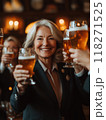 Portrait of beautiful elderly woman dressed in classic suit, raising glasses of beer and celebrating completed project with her female colleagues 118271525