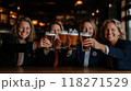 Group of cheerful women in business suits raising their glasses of beer, smiling and clinking glasses to celebrate successfully completed project, deal. 118271529