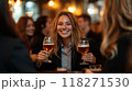 Group of women in business suits raising glasses of beer, smiling at cozy bar with soft, warm lighting 118271530