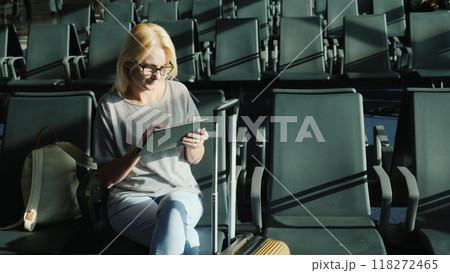 Caucasian woman is waiting for her flight. Sits in the airport terminal, uses a tablet 118272465