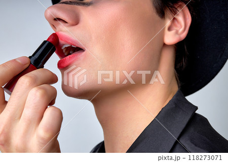 close-up androgynous man with party make-up applying pomade lipstick, isolated close-up androgynous man with party make-up applying pomade lipstick, isolated 118273071