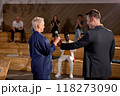 Rear view on man giving microphone to adult woman in formal wear for speaking 118273090