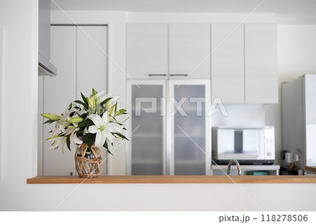 白基調のキッチンのカウンターに置いてある白い百合の花を活けてある花瓶 118278506