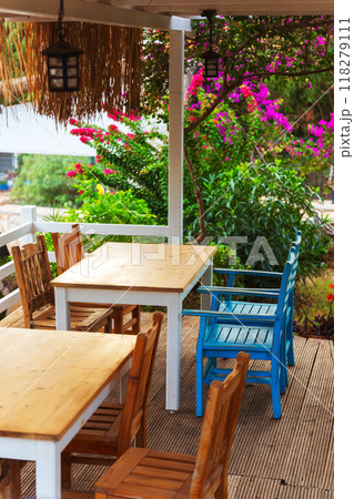 A spacious wooden deck that features tables and chairs arranged on it 118279111