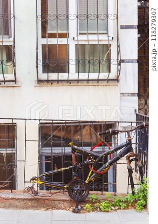 An old bicycle frame without wheels parked by a fence 118279307
