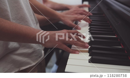 A teenage pianist and her dad play the piano, touching their fingers to the black and white keys to create the rhythm of the melody. People. Child development and entertainment. Art. Education A teenage pianist and her dad play the piano, touching their fingers to the black and white keys to create the rhythm of the melody. People. Child development and entertainment. Art. Education 118280738