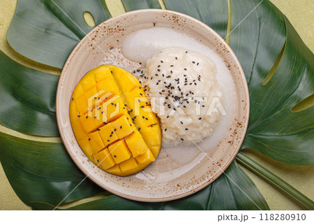 Traditional dessert of Thailand, delicious mango sticky rice with coconut milk and sesame seeds on tropical leaf top view 118280910