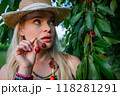 A portrait of a woman holding a bunch of cherries nad having red cherry juice on her lips 118281291