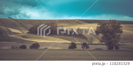 Rolling hills and lush fields define the agricultural landscape of Moravian Tuscany, showcasing vibrant colors under a dramatic sky, highlighting the natural beauty of Czechia's rural charm. 118281329