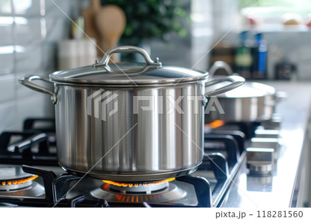 Close up of one grey large stainless steel pots with closed lids on kitchen stove, table illuminated by daylight from window. New clean kitchen utensils for canteen 118281560