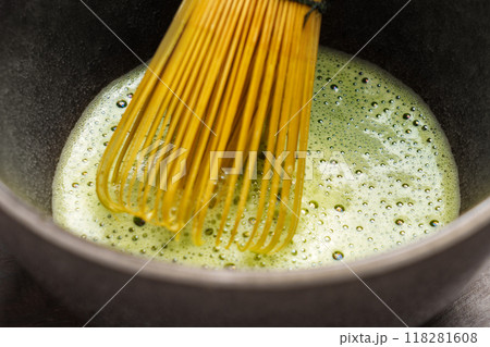 Freshly prepared organic matcha green tea in a bowl with a bamboo whisk. Traditional Japanese drink ceremony. Macro shot Freshly prepared organic matcha green tea in a bowl with a bamboo whisk. Traditional Japanese drink ceremony. Macro shot 118281608