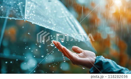 Hand Catching Raindrops Under an Umbrella on a Rainy Day 118282036