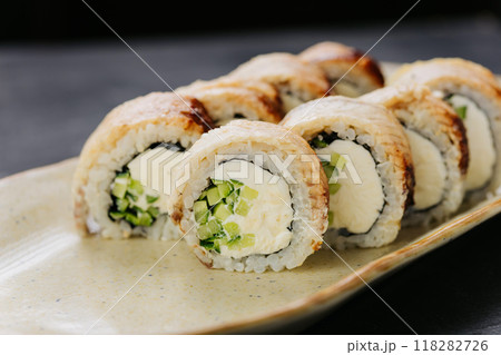 Grilled eel sushi rolls with cream cheese and cucumber on plate, perfect for Japanese cuisine lovers 118282726
