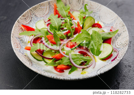 Colorful fresh salad with arugula, cucumbers, and tomatoes - a perfect dish for healthy eating  118282733