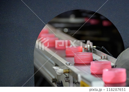 The row of pink plastic bottle caps ion the conveyor belt. 118287651