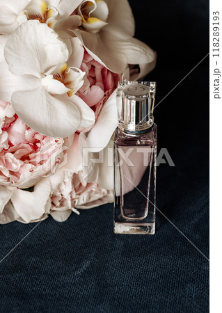 A bottle of perfume is on a table next to a bouquet of flowers 118289193