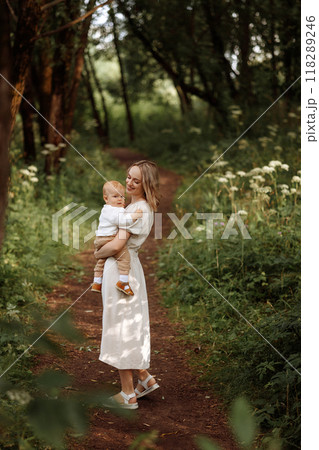 Happy woman holding a small child in her arms in the summer in a park 118289246