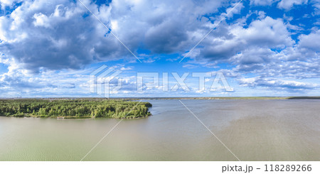 Big lake with green shores in bright sun light and city on horizon, aerial landscape. Recreation concept. Aerial view 118289266