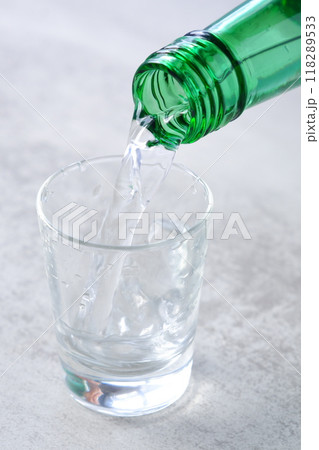 韓国の伝統的な蒸留酒、よく冷えた韓国焼酎（ソジュ）をグラスに注ぐ 118289533