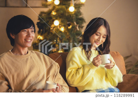 クリスマスツリーが飾ってある部屋でくつろぐ若いカップル 118289991