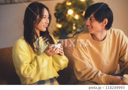 クリスマスツリーが飾ってある部屋でくつろぐ若いカップル クリスマスツリーが飾ってある部屋でくつろぐ若いカップル 118289993