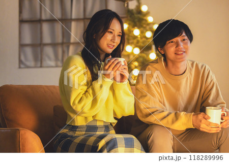 クリスマスツリーが飾ってある部屋でくつろぐ若いカップル クリスマスツリーが飾ってある部屋でくつろぐ若いカップル 118289996