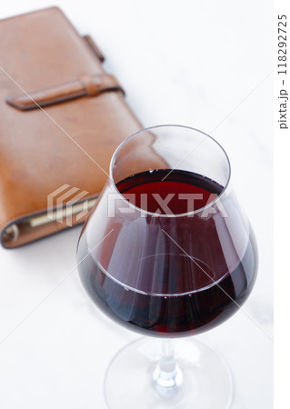 赤ワインを飲みながら、茶色の革のシステム手帳に日記をつけているイメージ 118292725