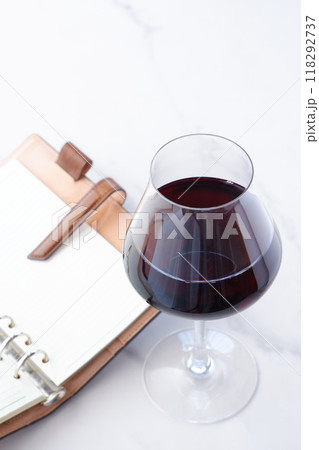 赤ワインを飲みながら、リング式のシステム手帳に日記をつけているイメージ写真 118292737