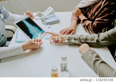 Medical professional showing x-ray results to patient in consultation room. Focus on discussing treatment options and diagnosis during appointment Medical professional showing x-ray results to patient in consultation room. Focus on discussing treatment options and diagnosis during appointment 118293108