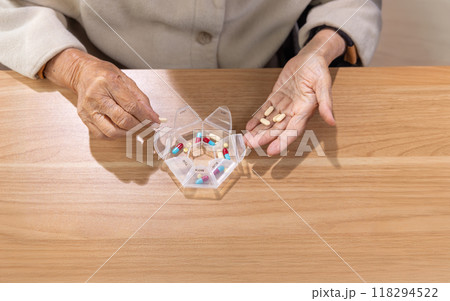 Elderly woman putting pills into pill box for the week. 118294522