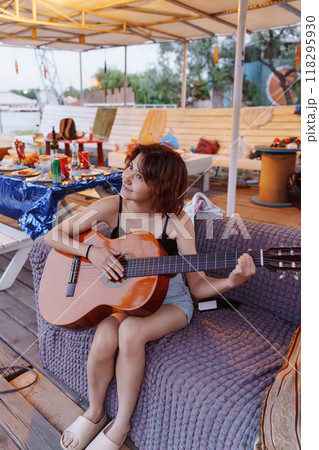 Funny young woman with guitar at picnic. Summer party on the beach. 118295930