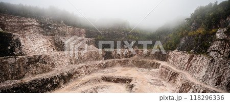 A limestone quarry in Cerny Dul, nestled in the Giant Mountains, features steep, rocky cliffs and a misty atmosphere, highlighting the area's industrial activity and natural beauty. 118296336