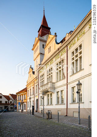 The historic Town Hall stands proudly in Stara Boleslav, showcasing elegant architecture under the golden light of dusk. Cobbled streets invite visitors to explore the charming surroundings. 118296339